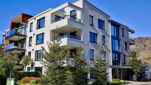 A multi-story residential building with balconies, large windows, and a sign indicating it is a residential complex. - Apres Escape - 3 Bed (Queenstown)