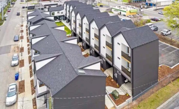 Una hilera de edificios residenciales modernos, de varios pisos y con techos inclinados, frente a un estacionamiento.