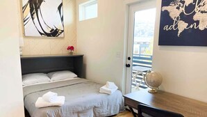 Un dormitorio con cama, escritorio, silla, un globo terráqueo y un mapa del mundo en la pared.
