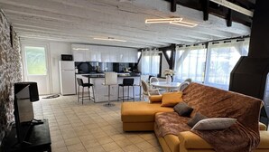 Ein modernes Wohnzimmer mit Sofa, Fernseher und Essbereich mit Tisch und Stühlen.