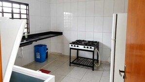 A compact kitchen with white tiled walls, a black countertop, a gas stove, and a white refrigerator.