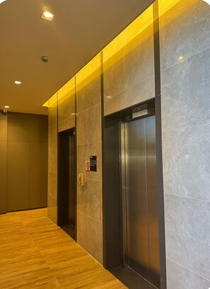 A modern elevator with a digital display, a telephone, and a no-smoking sign. - Cozy studio across from the Botanical Garden in Curitiba, PR (Curitiba)