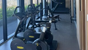 Ein Fitnessraum mit Cardiogeräten, Langhantelbänken und Kurzhanteln.