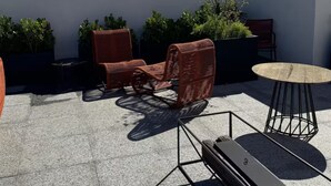 Eine Dachterrasse mit Gartenmöbeln, einem Tisch und Topfpflanzen.