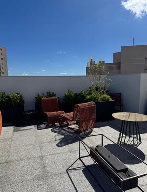 A rooftop terrace with outdoor furniture, a table, and potted plants. - Cozy studio across from the Botanical Garden in Curitiba, PR (Curitiba)
