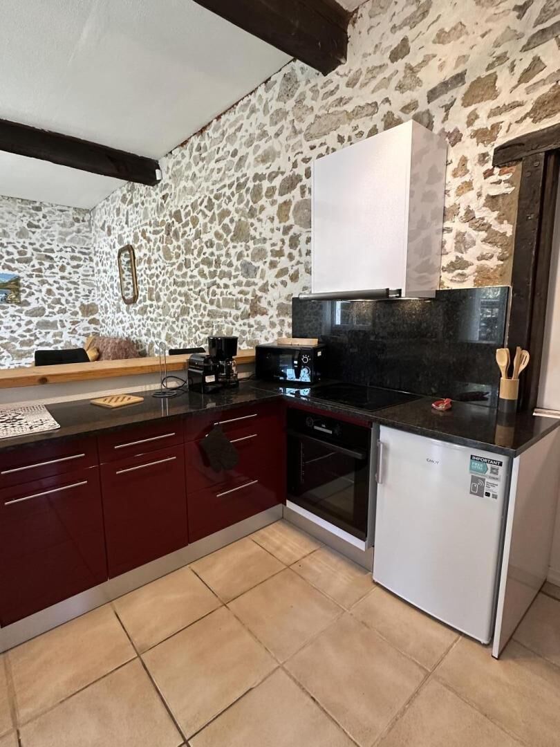 A kitchen with a stone wall, a black countertop, a white refrigerator, and a stove.