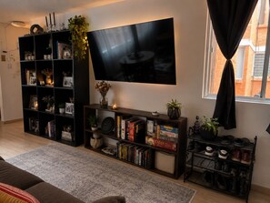 Ein Wohnzimmer mit Flachbildfernseher, Bücherregalen, einem Couchtisch und einem Schuhschrank.