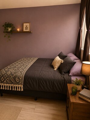 Ein Schlafzimmer mit einem Bett, Kissen, einem Nachttisch mit Lampe, einer kleinen Pflanze und einem gerahmten Bild auf einem Regal.