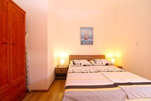Une chambre à coucher comprenant un lit, deux lampes de chevet, une table de chevet, une armoire en bois et un tableau accroché au mur.