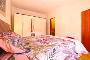 Une chambre à coucher avec un lit, une armoire et une salle de bain visible à travers une porte ouverte.