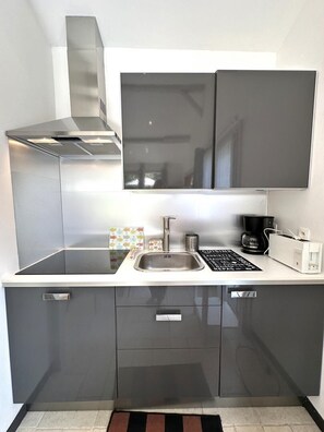 Eine moderne Küche mit einer Edelstahl-Dunstabzugshaube, einer Spüle und einer Kaffeemaschine.