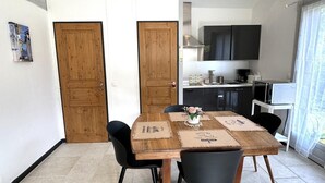 Een eethoek met een houten tafel, zwarte stoelen en een keuken op de achtergrond.