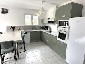 Una cocina moderna equipada con lavavajillas, doble pileta, microondas, horno y refrigerador.