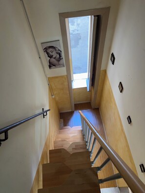 Eine Treppe mit Holzboden und Metallgeländern, eine Tür, die zu einem Außenbereich führt, und ein an der Wand befestigtes Bild.