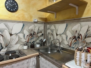 A kitchen with a clock, a sink, a stove, and a decorative wall. - Toledo Loft San Liborio (Napoli)