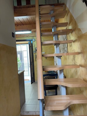 A wooden staircase with a handrail, a tiled floor, and a door leading to an outdoor area. - Toledo Loft San Liborio (Napoli)