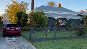 A residential house with a fenced yard, a car parked in the driveway, and a chimney.