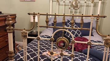 A bed with a metal frame, a patterned bedspread, and a decorative mirror.