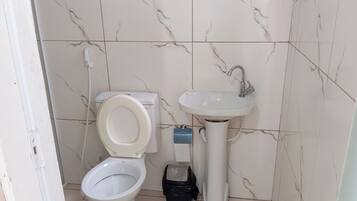 A bathroom with a toilet, sink, and a black trash bin.
