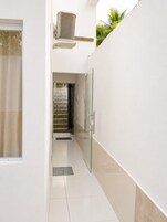 Um corredor limpo e moderno, com porta de vidro, escada de metal e unidade de ar condicionado na parede.