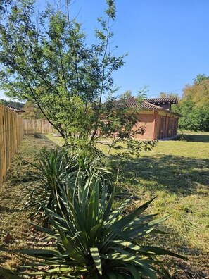 A fenced yard with a small building, a tree, and a plant. - COUDERE House - SOUSTONS (SOUSTONS)