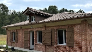 A brick building with a tiled roof, multiple windows with shutters, and a door. - COUDERE House - SOUSTONS (SOUSTONS)