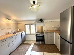 A modern kitchen with a dishwasher, stove, oven, and refrigerator. - COUDERE House - SOUSTONS (SOUSTONS)