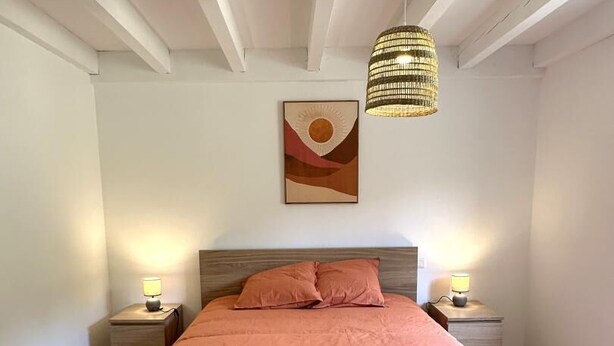 A bedroom with a large bed, two bedside tables with lamps, a hanging light fixture, and a painting on the wall. - COUDERE House - SOUSTONS (SOUSTONS)