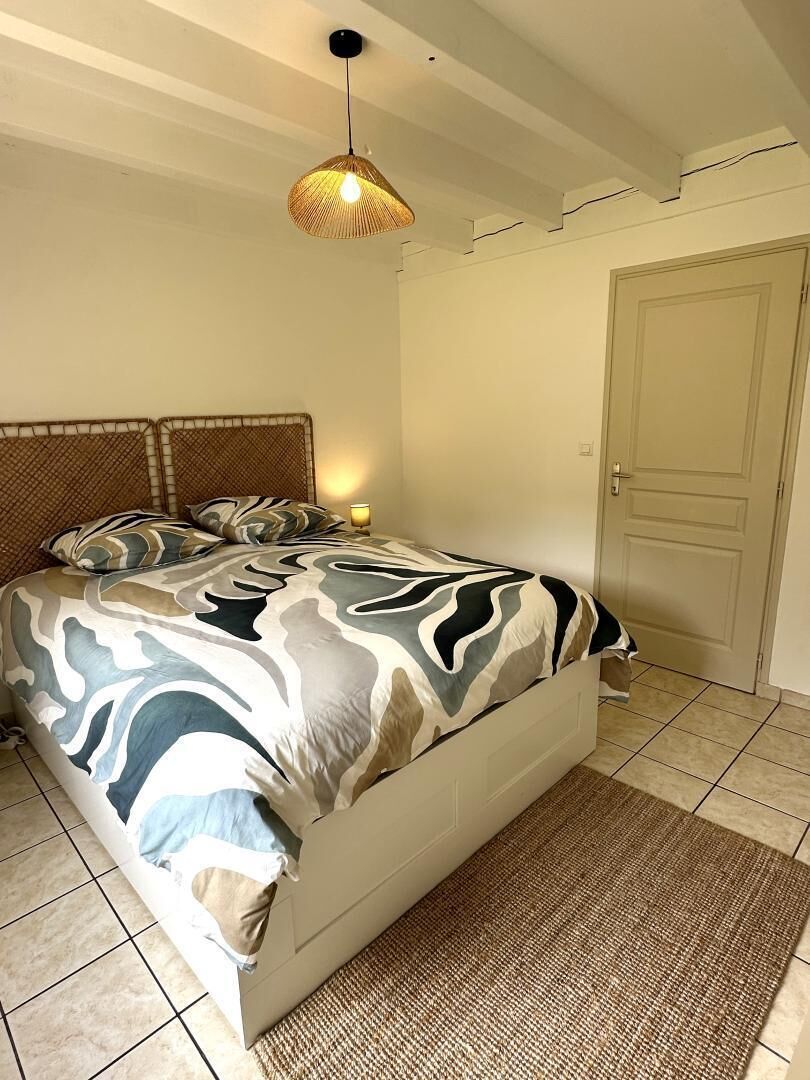 A bedroom with a bed, a woven headboard, a door, and a textured rug.