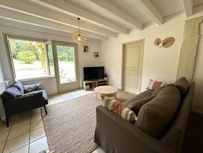A living room with a sofa, TV, and a dining table. - COUDERE House - SOUSTONS (SOUSTONS)
