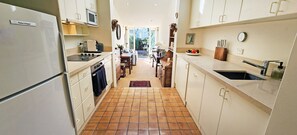 A narrow kitchen with white cabinets, a refrigerator, a microwave, and a sink. - Paddington Central Sydney - Sunlit Courtyard (Paddington)