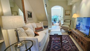 Ein Wohnzimmer mit einer Couch, einem Couchtisch, einem Fernseher und einem gemusterten Teppich.