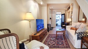 Ein Wohnzimmer mit einer Couch, einem Fernseher, einem gemusterten Teppich und einer Treppe.