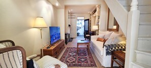 A living room with a sofa, a TV, a patterned rug, and a staircase. - Paddington Central Sydney - Sunlit Courtyard (Paddington)