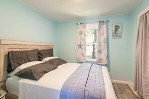 Quarto com cama, cortinas e janela.