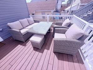 Eine Terrasse mit Korbmöbeln und einem weißen Geländer.
