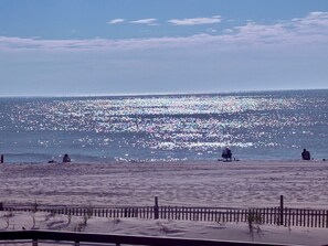 Une plage où l’on voit des gens assis et se promenant le long du rivage.