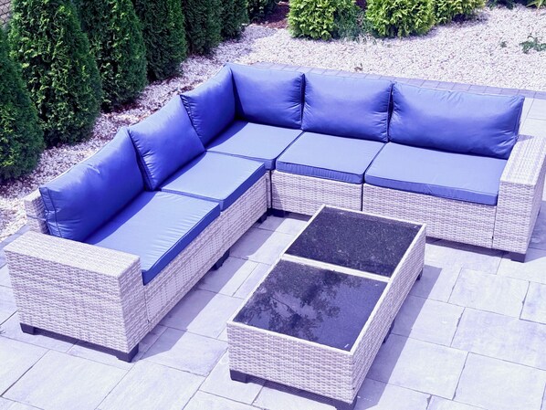 Ein modulares Sofa für draußen mit Kissen und einem quadratischen Tisch.