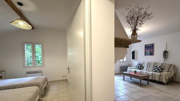 Una habitación con dos camas, una ventana, un sofá, una mesa y una planta colgante.