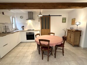 Une cuisine avec une table ronde, des chaises, une cuisinière et un meuble de rangement.