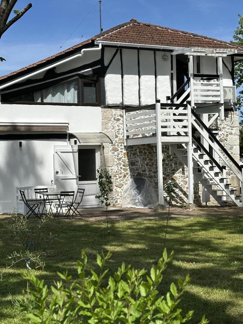 Een huis met twee verdiepingen, een stenen gevel, een houten trap en een klein terras.