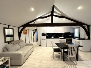 A modern kitchen with white cabinets, a black countertop, and a dining area with a table and chairs. - PATXI - DAX - City Break (DAX)