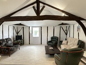 A loft-style room with exposed wooden beams, a television, a sofa, a chair, and a coffee table. - PATXI - DAX - City Break (DAX)