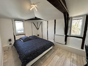Ein Schlafzimmer mit Bett, Fenster, Heizkörper und Deckenleuchte.