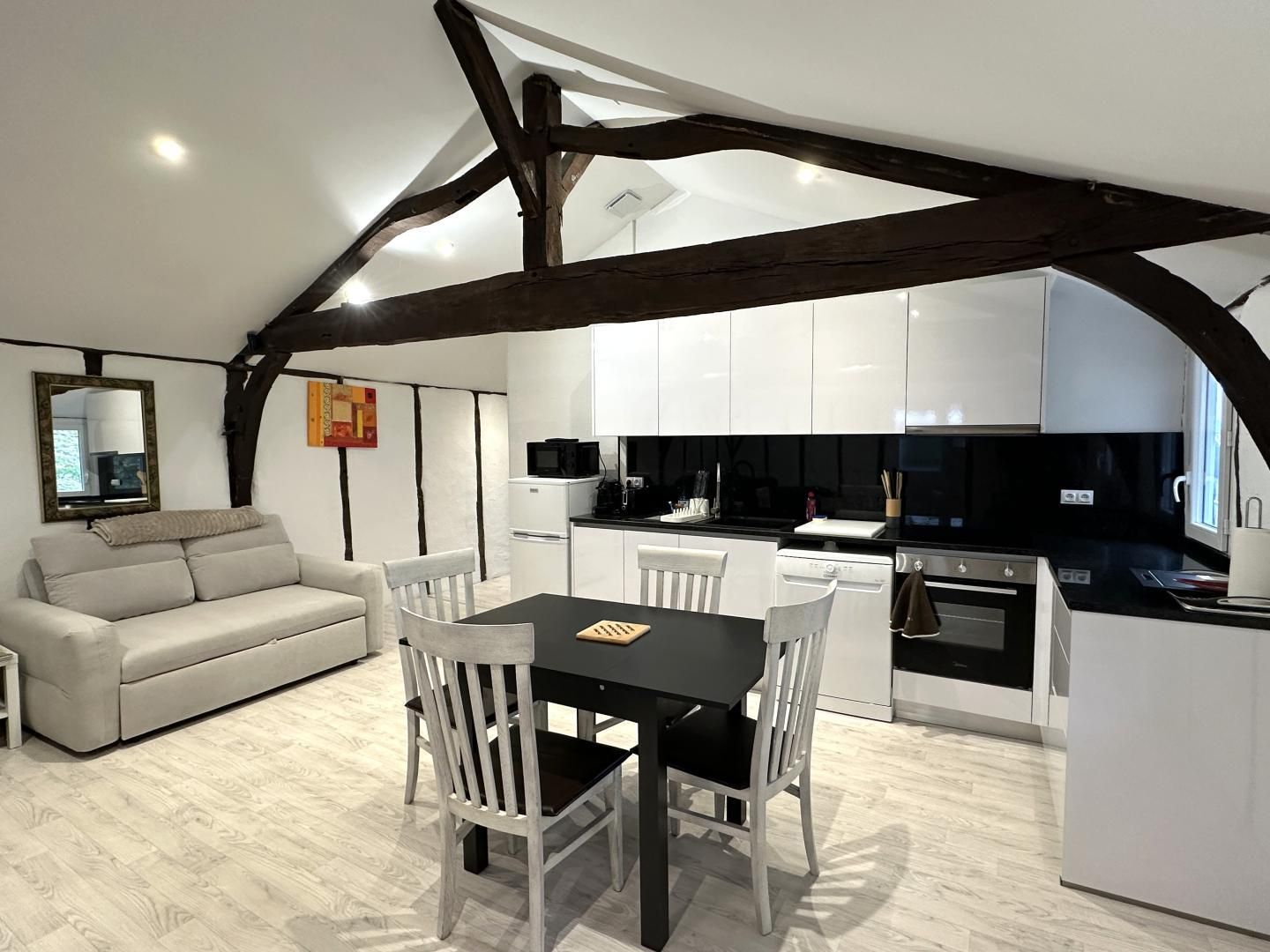 A modern kitchen with white cabinets, a black countertop, and a dining area with a table and chairs.