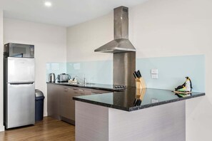 A modern kitchen with a stainless steel range hood, a built-in microwave, and a granite countertop.