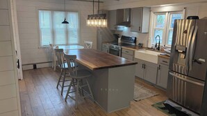 Eine moderne Küche mit einer zentralen Kochinsel, Edelstahlgeräten und einem Essbereich mit einem Holztisch und Stühlen.