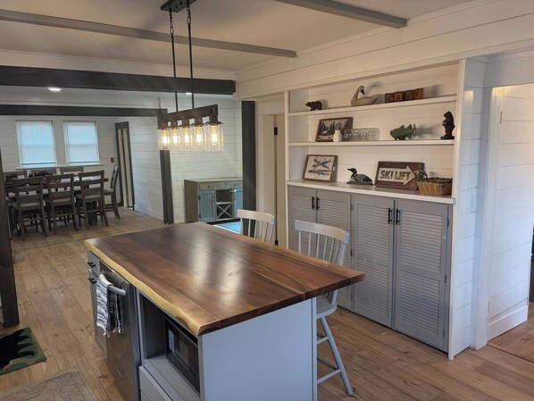 A kitchen with a wooden island, white cabinets, and a hanging light fixture.