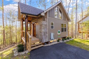 Eine Holzhütte mit Natursteinfassade, einer Holzdiele und freiem Blick auf den umliegenden Wald.