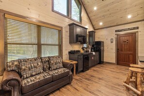 Ein Ferienhäuschen-Interieur mit einer Couch, Küchenzeile, Holzböden und einem Schild, das auf den Appalachian Trail hinweist.